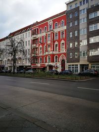 Road by buildings against sky in city