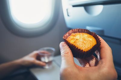 Close-up of hand holding cupcake in airplane