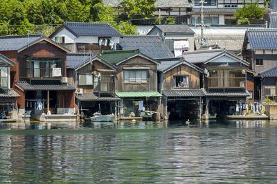 Houses by lake against buildings in city
