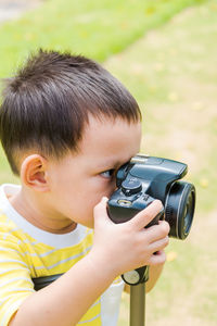 Cute boy photographing while standing at park