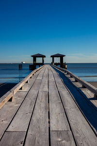 Pier over sea against clear blue sky