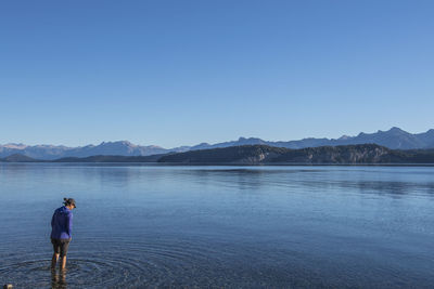 Woman trying the water at nahuel huapi lake in patagonia