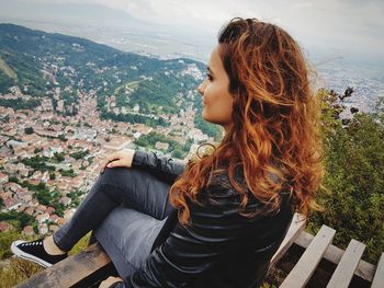 Beautiful woman sitting on table against sky