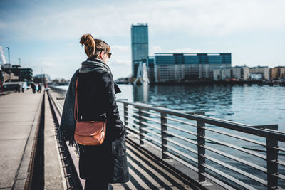 Rear view of woman on bridge against cityscape