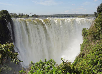 Scenic view of waterfall against sky