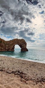 Rock formation on beach against sky