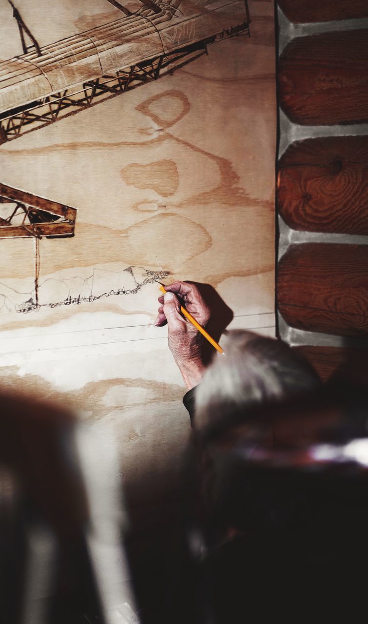 HIGH ANGLE VIEW OF MAN HOLDING PAPER AT HOME