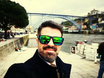 Portrait of smiling businessman wearing sunglasses with bridge in background