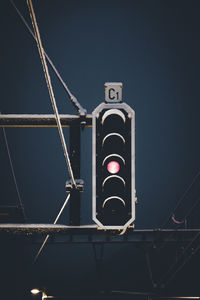 Low angle view of illuminated red light signal against sky during winter