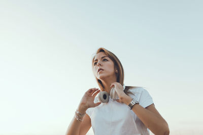 Young women looking away while standing on field against sky