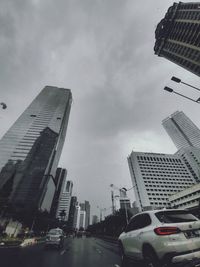 Cars on road by buildings against sky in city