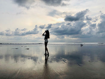 Woman standing on beach against sky