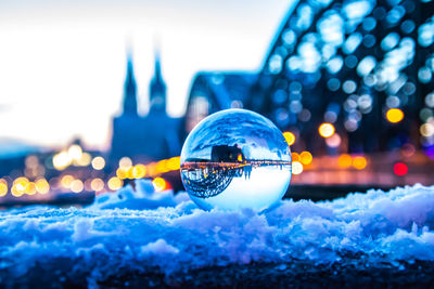 Close-up of crystal ball against illuminated city in winter