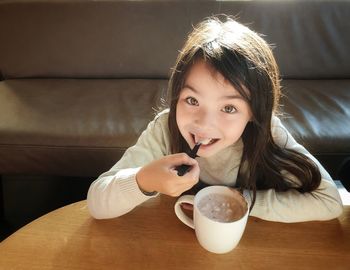 Portrait of a smiling young woman drinking coffee at home