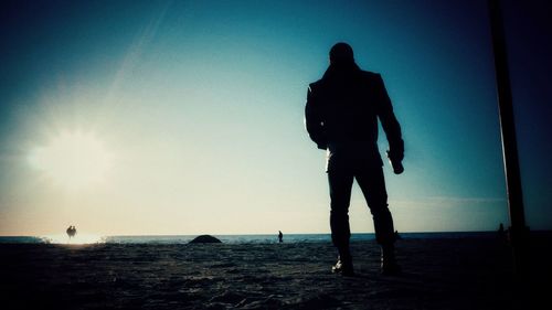 Silhouette men standing on beach against sky during sunset