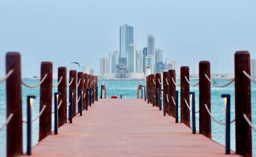 Wooden pier in sea against clear sky. waterfront view of manama, bahrain