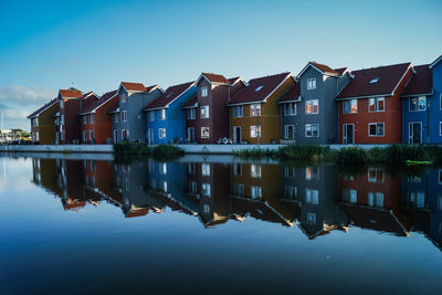 Reflection of buildings in lake against blue sky