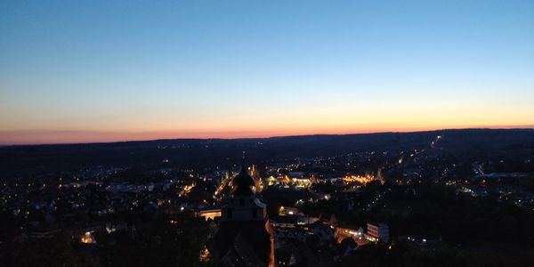 Aerial view of illuminated city against sky at sunset