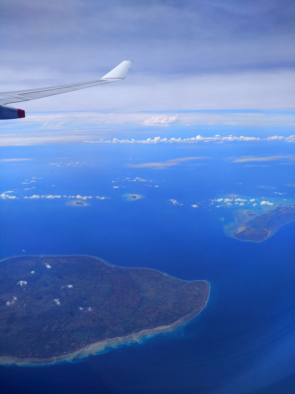 AERIAL VIEW OF SEA AND AIRPLANE FLYING OVER CLOUDS