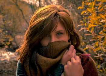 Close-up portrait of young woman with autumn leaves