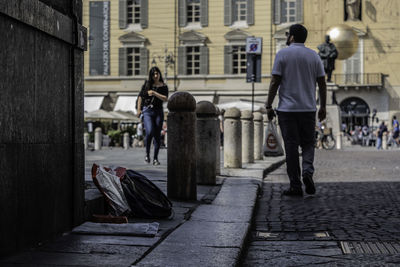 Rear view of people walking on sidewalk in city