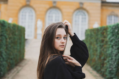 Portrait of young woman standing against building