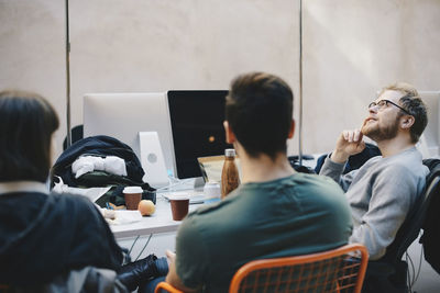 Thoughtful computer programmer sitting with colleagues in office