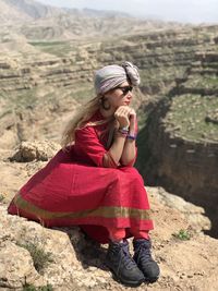 Side view of young woman sitting on rock