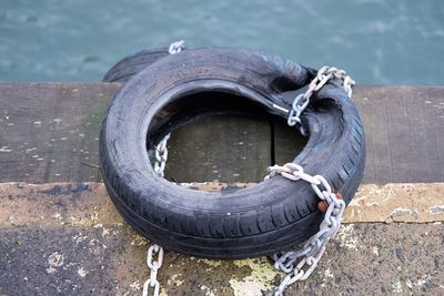 High angle view of tire tied with chain on pier