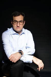 Mid adult man wearing sunglasses standing against black background