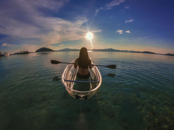 Man in sea against sky during sunset