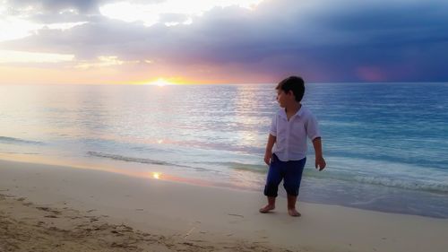 Full length of woman standing on beach during sunset