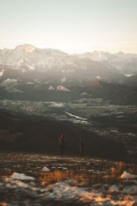People walking against scenic view of mountains and sky