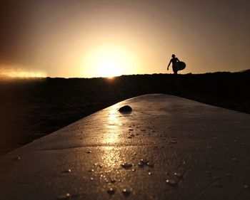 Silhouette man on shore against sky during sunrise