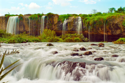 Scenic view of waterfall against sky