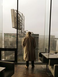 Rear view of man standing against sky in city