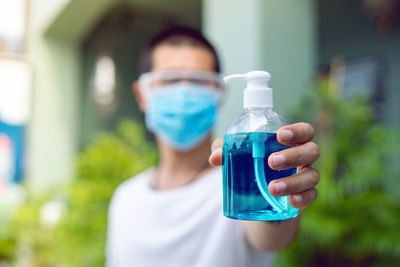 Close-up of man holding bottle against blurred background