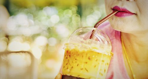 Midsection of woman drinking cold drink