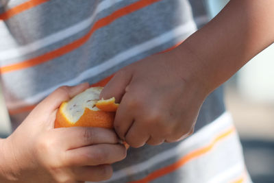 Close-up of child's hand peeling an orange