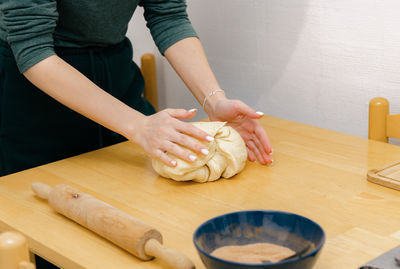 The hand of a caucasian young girl kneads dough on the table.