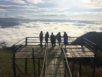 People standing by railing against sky