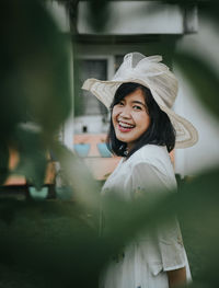 Portrait of cheerful young woman wearing hat standing outdoors