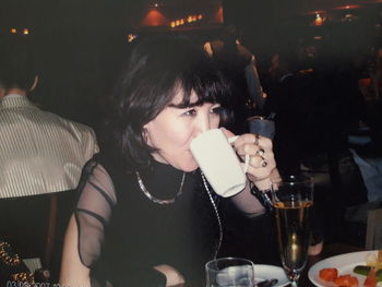 Portrait of young woman drinking glass at restaurant