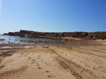 Scenic view of sandy beach against clear blue sky