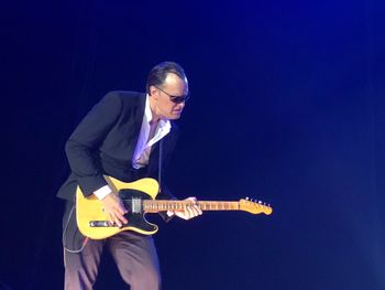 Man playing guitar against blue sky