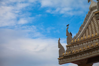 Low angle view of pigeons perching on temple against sky