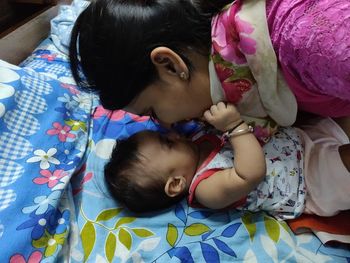 Close-up of mother and baby boy lying on bed at home