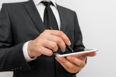 Midsection of businessman with mobile phone against white background