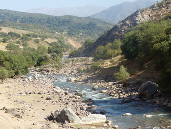 Scenic view of river by mountains against sky