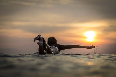 Indonesia, bali, female surfer in the ocean at sunset